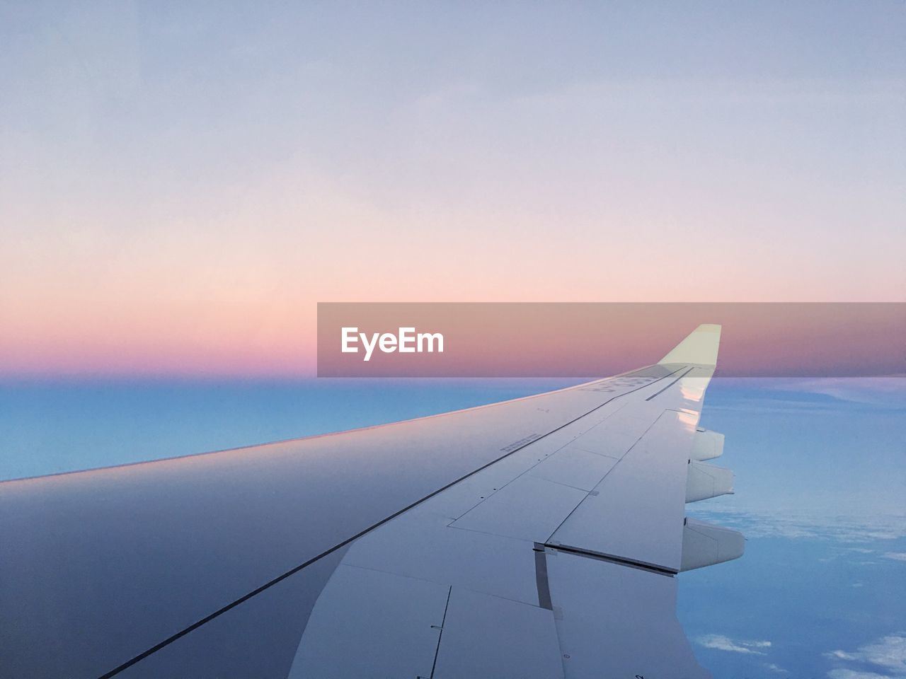 AIRPLANE WING OVER SEA AGAINST SKY