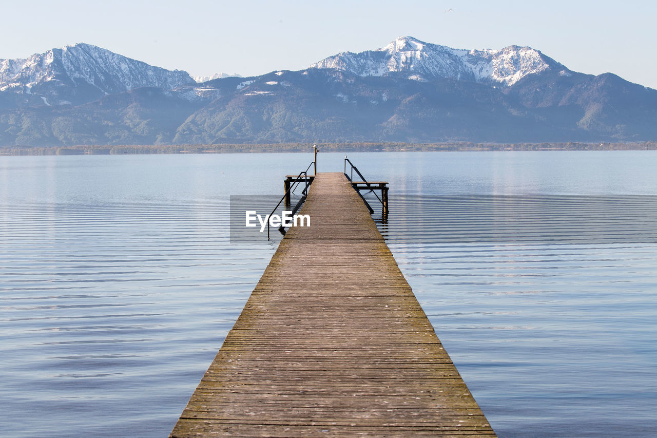 Narrow jetty at calm lake