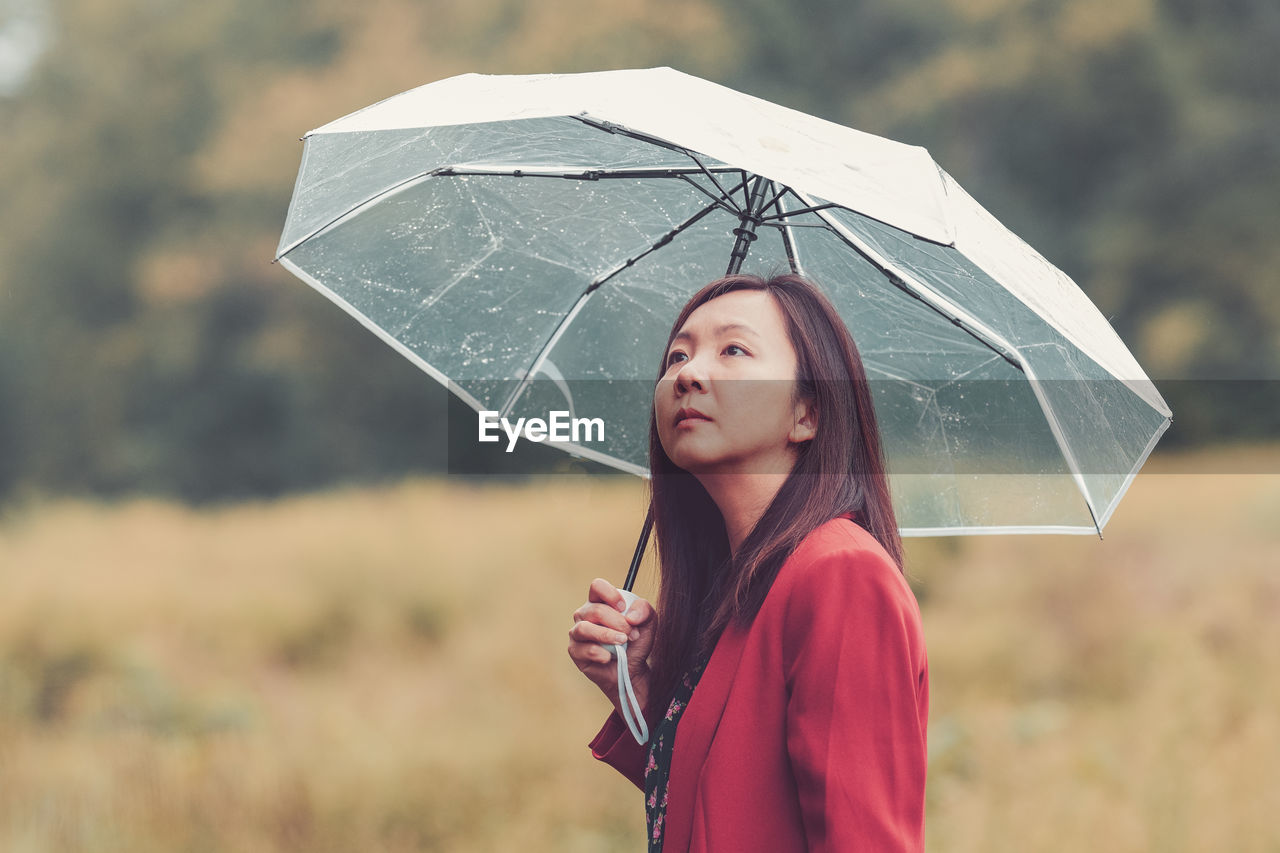 Portrait of woman with umbrella standing during rainy season