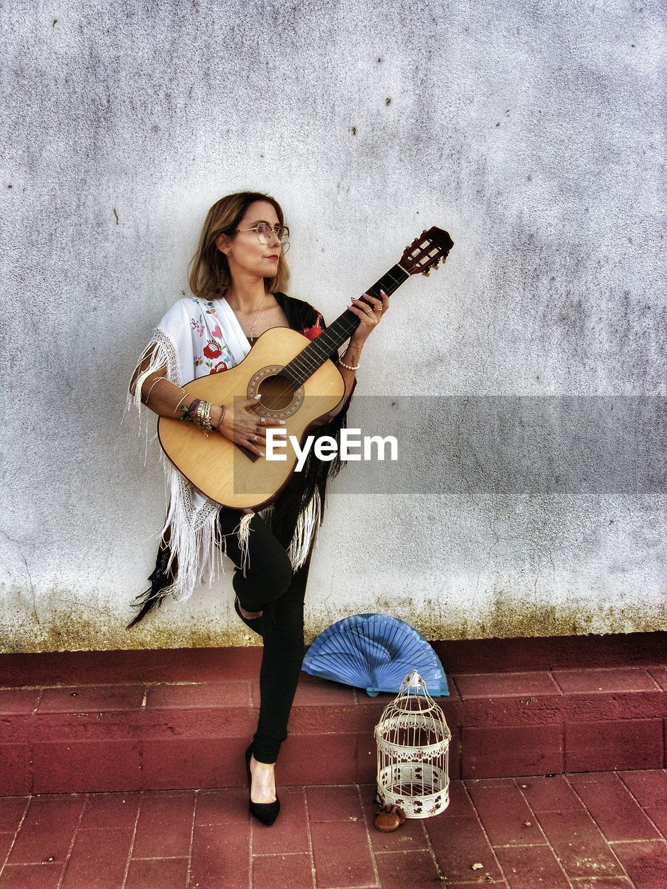 YOUNG WOMAN PLAYING GUITAR ON WALL