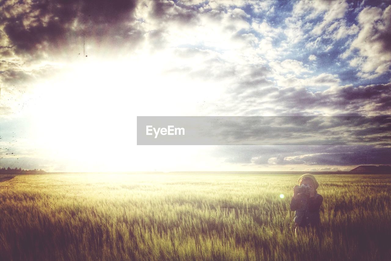 Girl photographing in grassy field