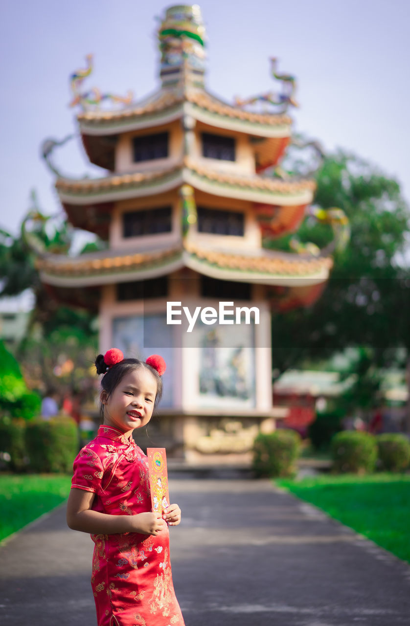 Portrait of smiling girl standing against built structure