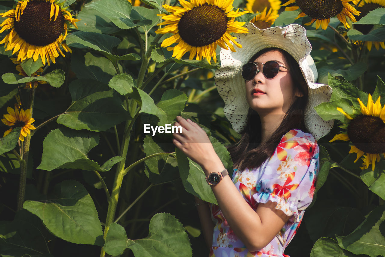 Young woman standing by yellow flowering plants