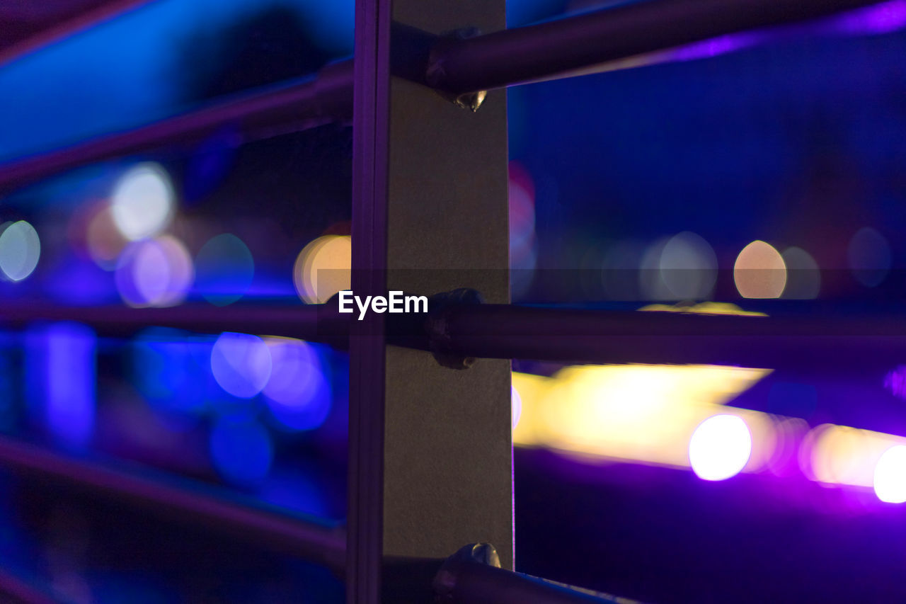 Close-up of railing in illuminated city at night