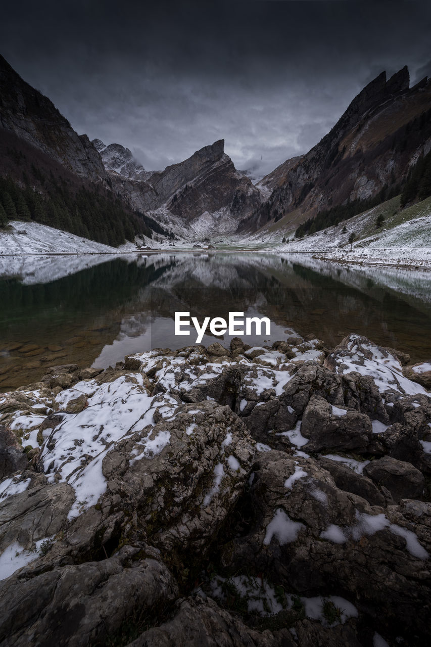 Scenic view of lake by snowcapped mountains against sky