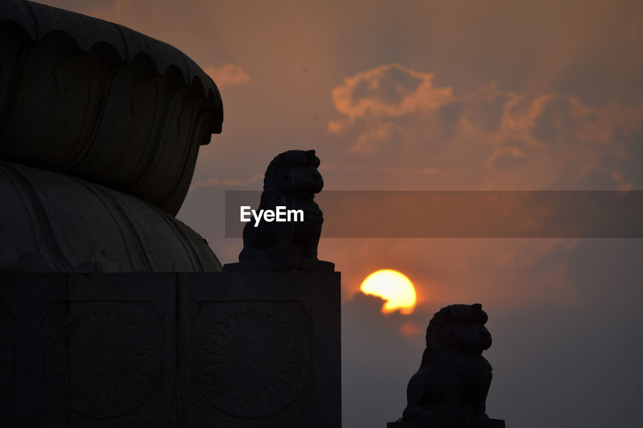 SILHOUETTE OF STATUE AGAINST SUNSET SKY