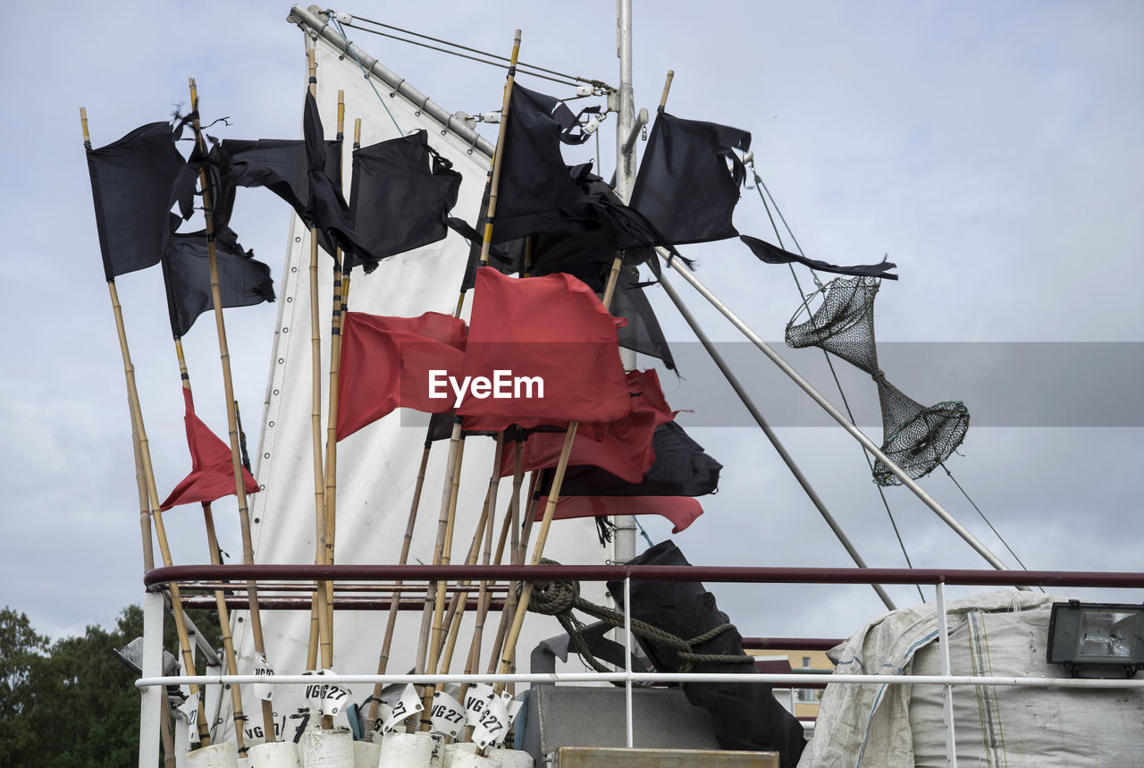 Red and black flags on trawler against sky