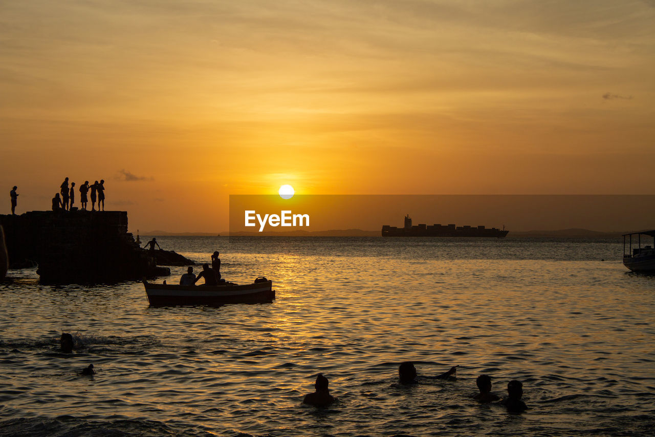 Sunset on beach with boats and people