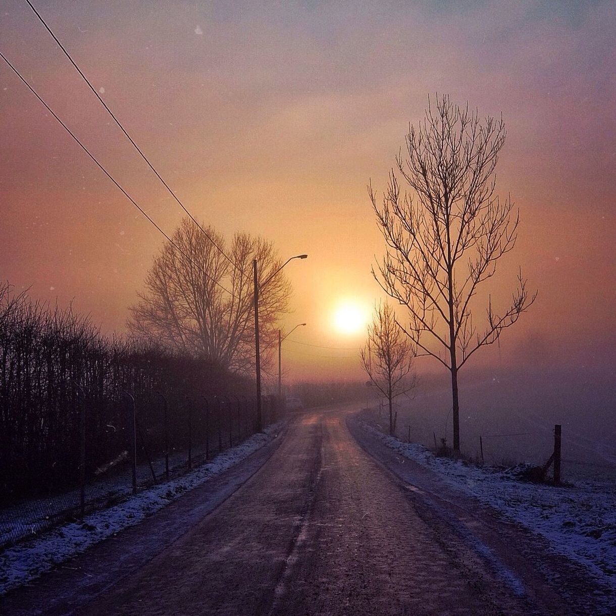 Empty road against cloudy sky at sunset