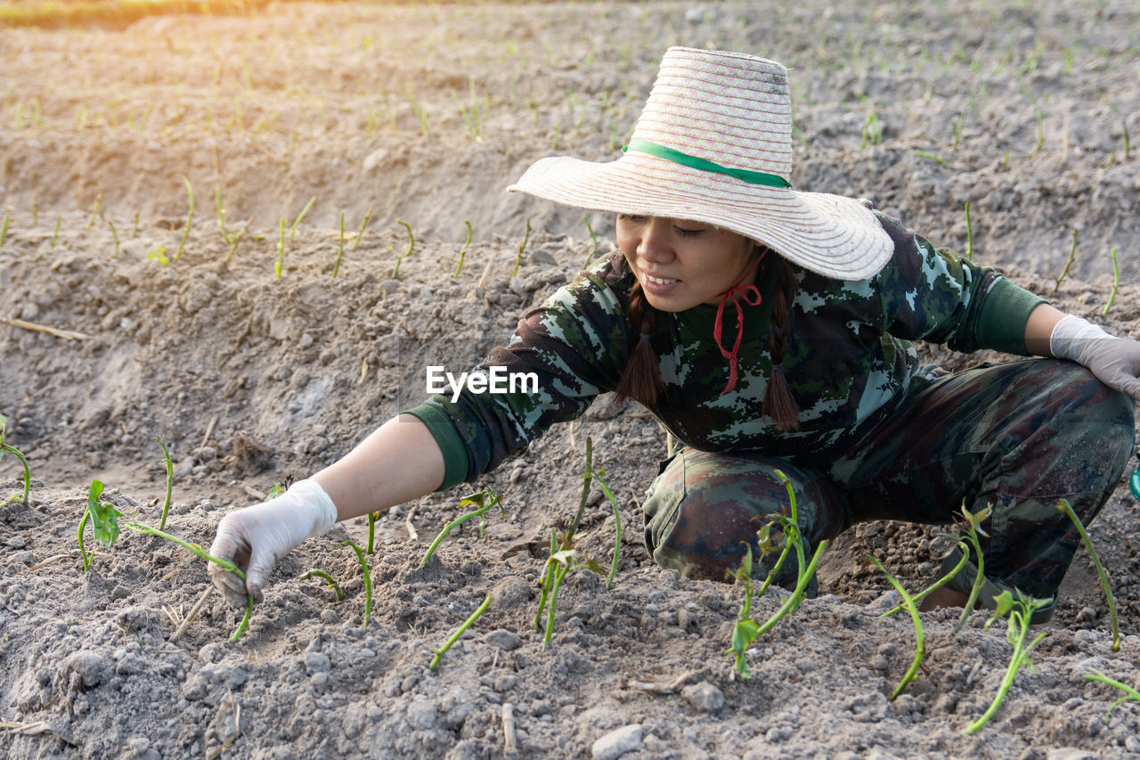 High angle view of woman crouching while plants in farm