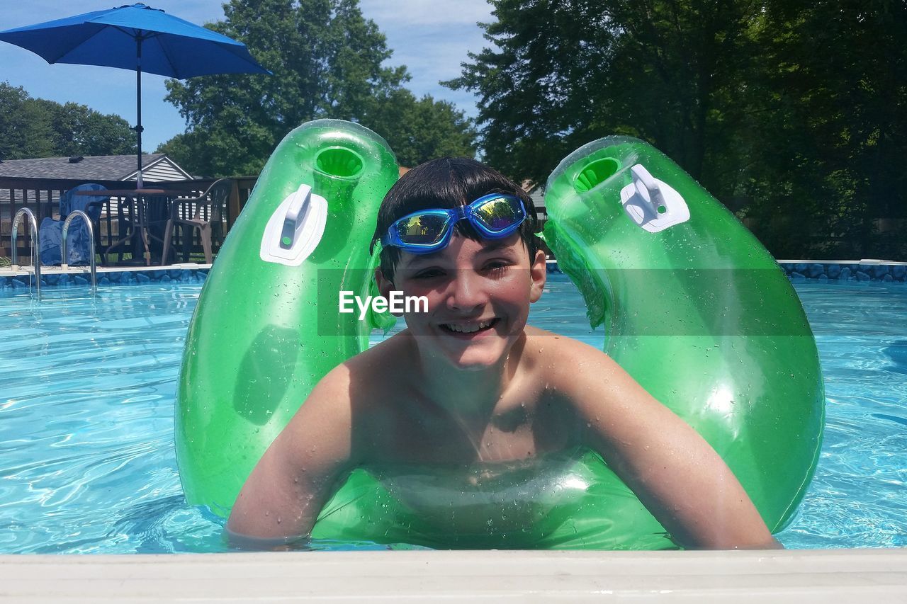 Portrait of smiling boy with inflatable ring in swimming pool