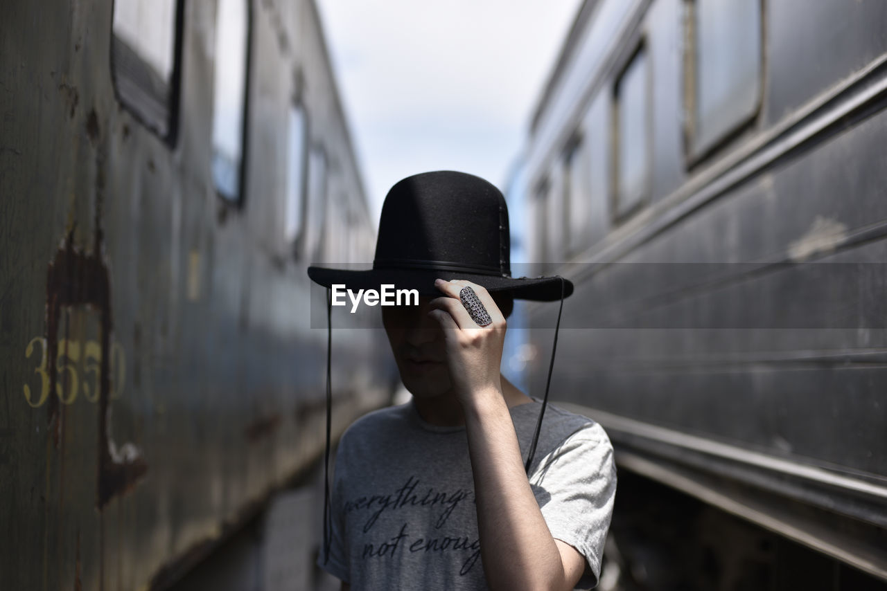 Man wearing hat against trains