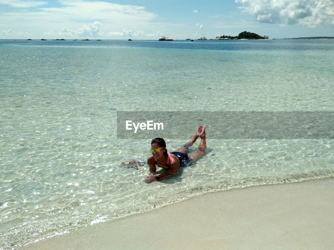 BOY SITTING ON BEACH AGAINST SKY