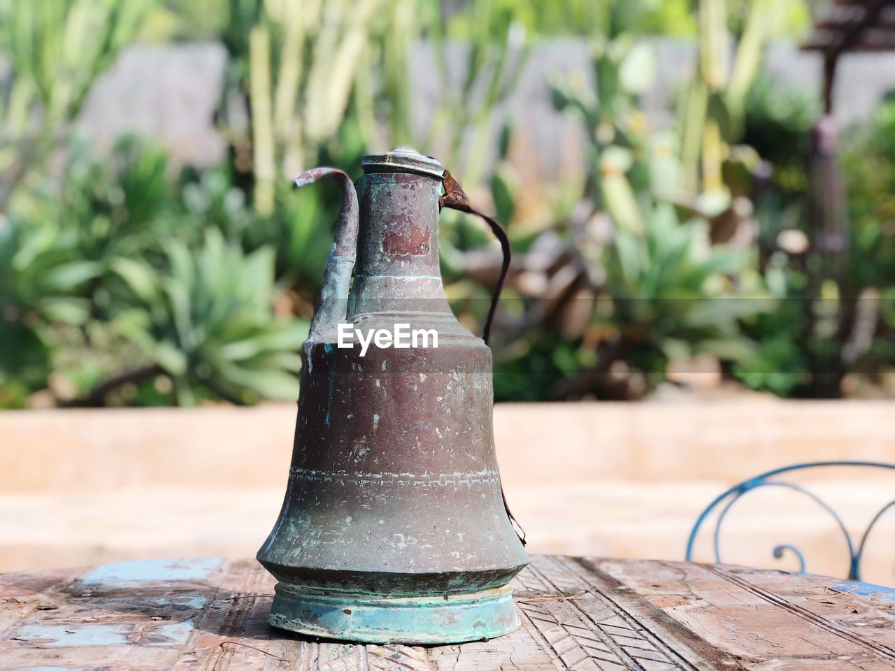 CLOSE-UP OF METALLIC CONTAINER ON TABLE BY PLANTS