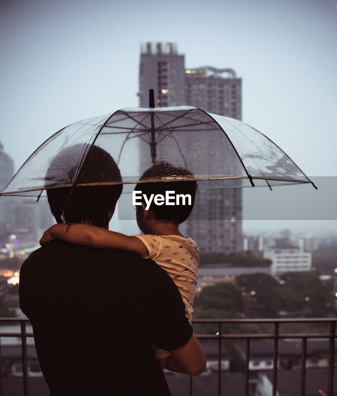 MAN AND WOMAN STANDING BY BUILDING AGAINST SKY