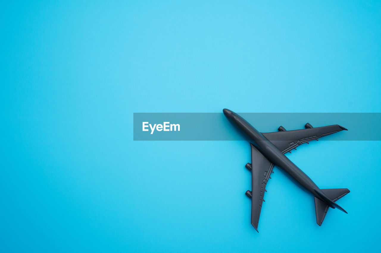 Travel concept flat lay design with airplane on blue background with copy space.