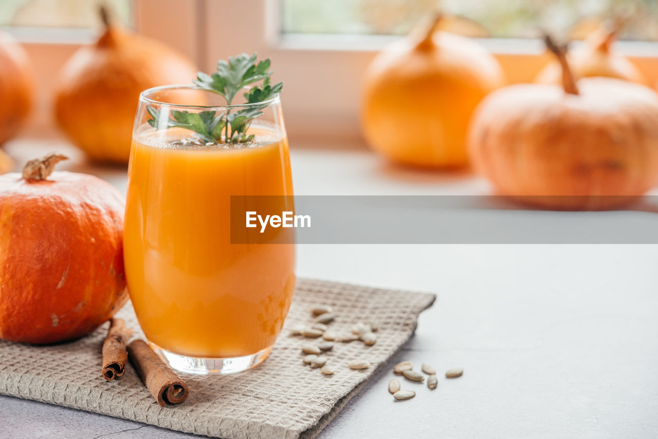 food and drink, food, healthy eating, freshness, fruit, drink, wellbeing, orange color, refreshment, household equipment, produce, glass, no people, drinking glass, plant, vegetable, indoors, wood, pumpkin, herb, juice, focus on foreground, table, spice, nature, leaf