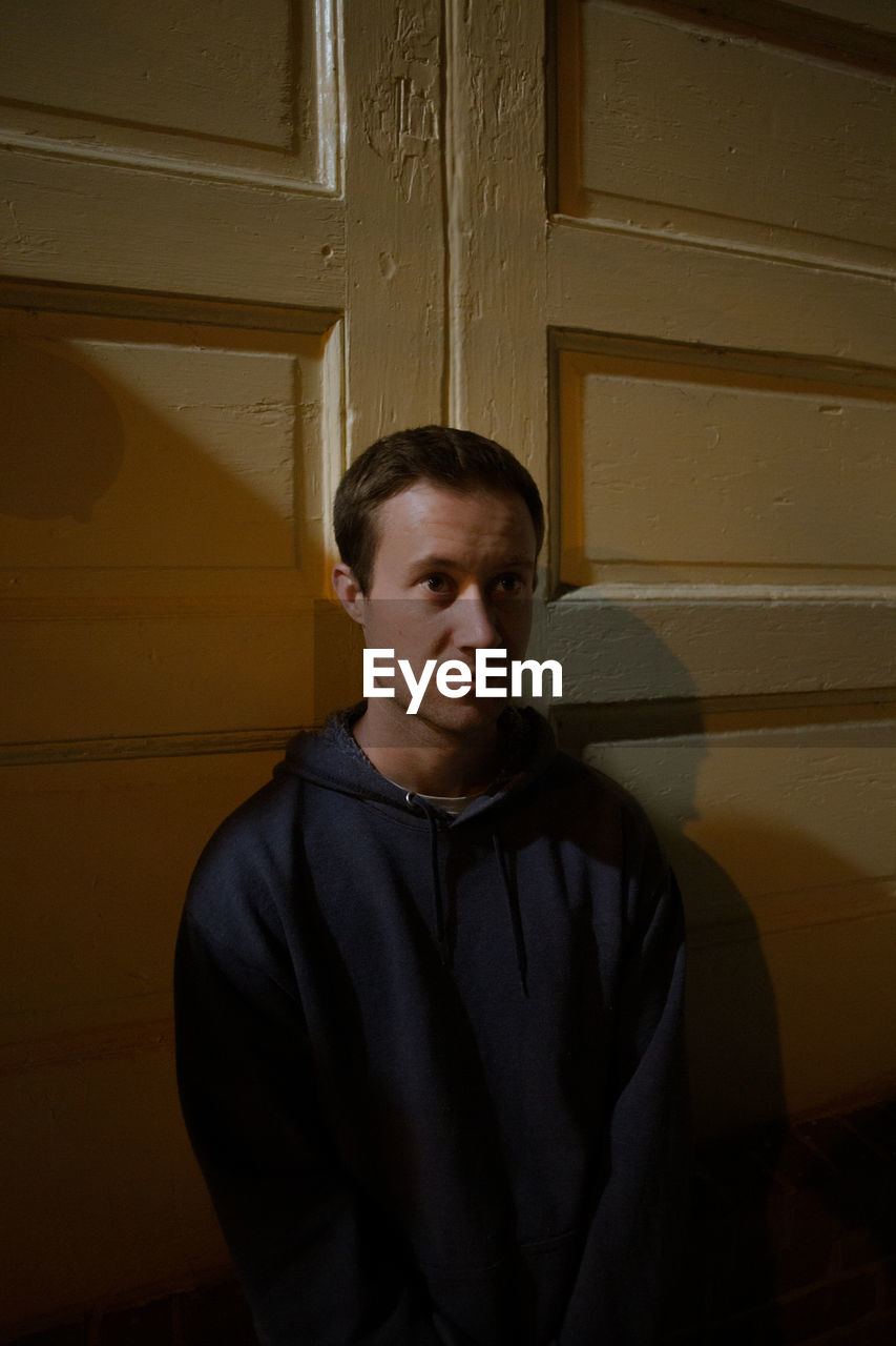 PORTRAIT OF A MAN STANDING AGAINST WALL