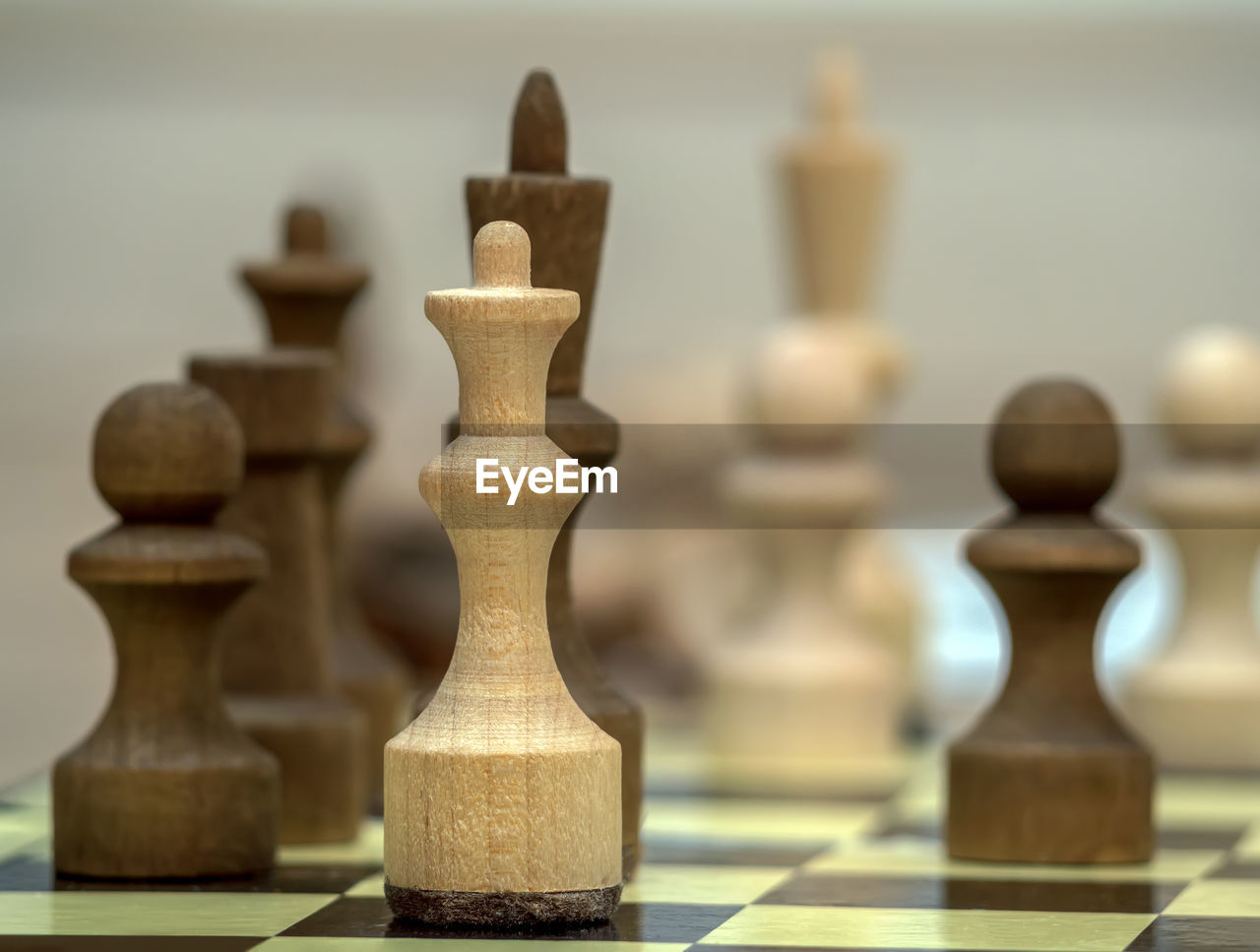 Vintage wooden chess pieces on the chess board. white chess queen put in check. close-up.