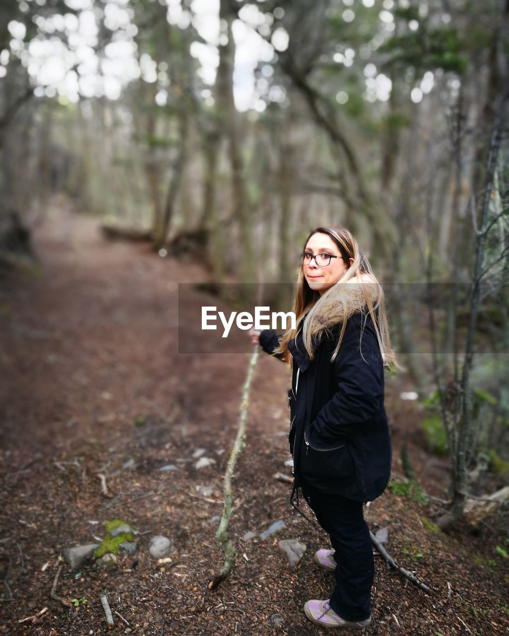 Woman walking on dirt road in forest