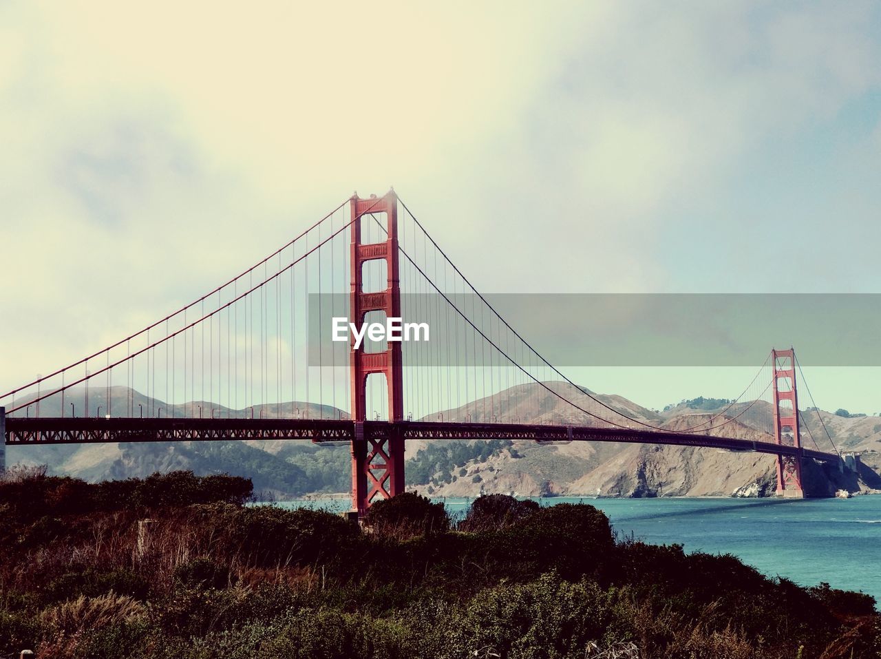 Golden gate bridge over water in city against sky