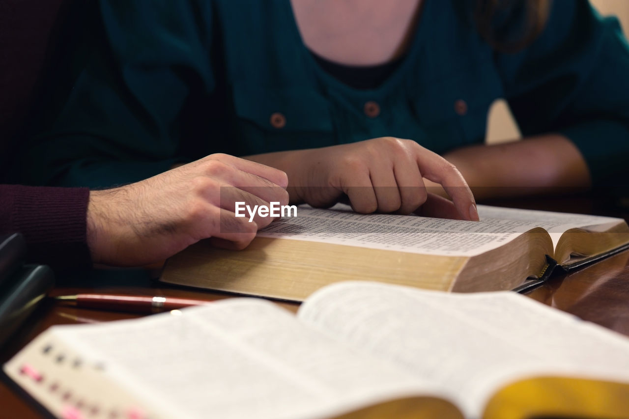 MIDSECTION OF MAN HOLDING BOOK ON TABLE