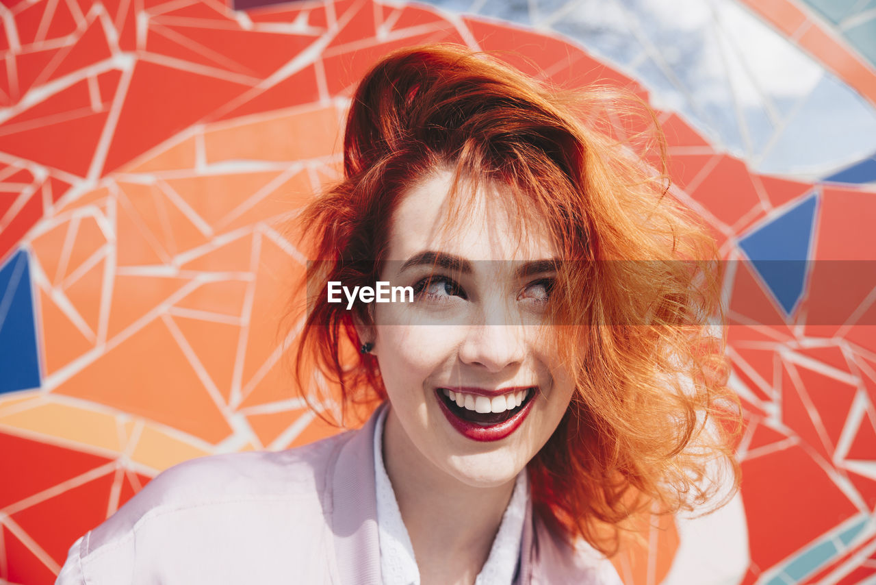 Smiling redhead young woman against mosaic wall