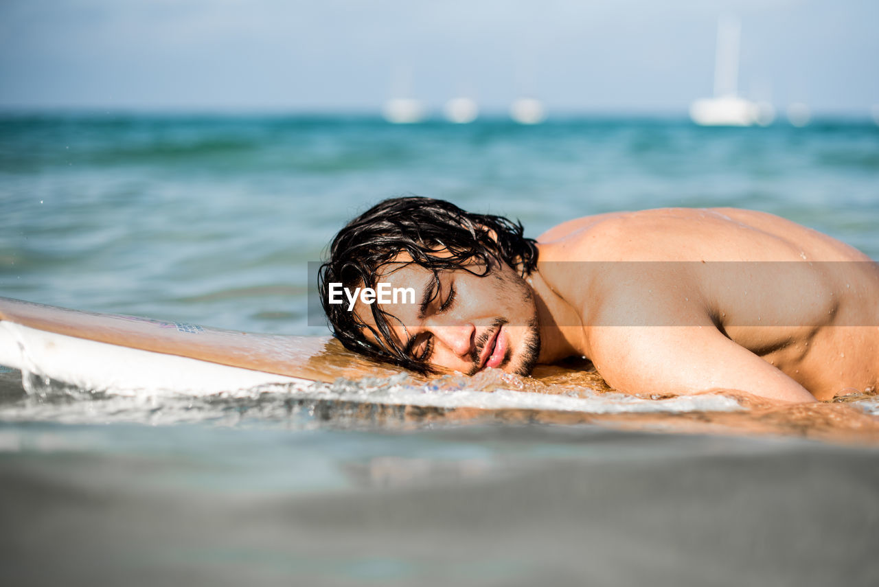 PORTRAIT OF SHIRTLESS YOUNG MAN IN WATER
