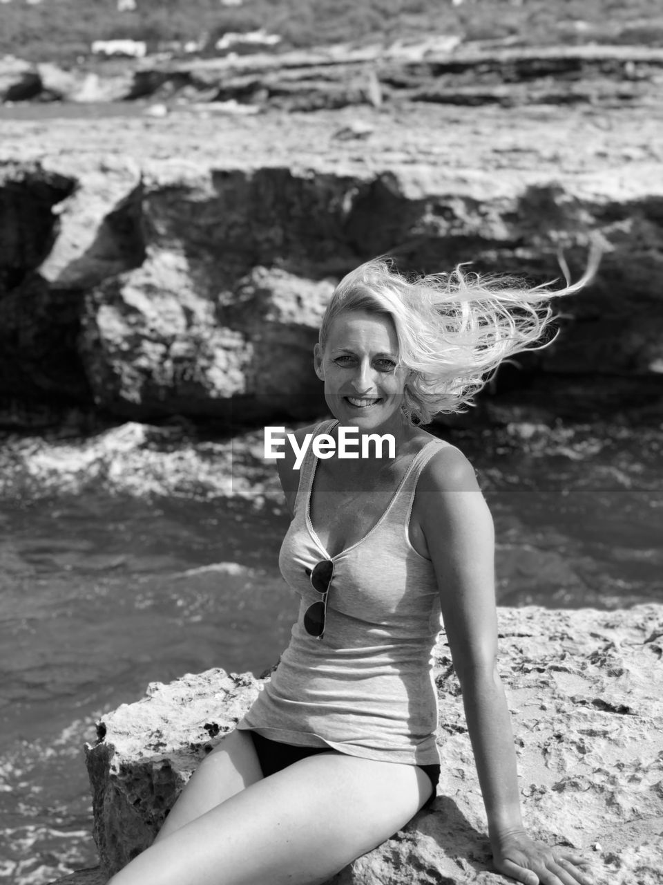 Beautiful woman sitting on a rock the wind blowing through her hair