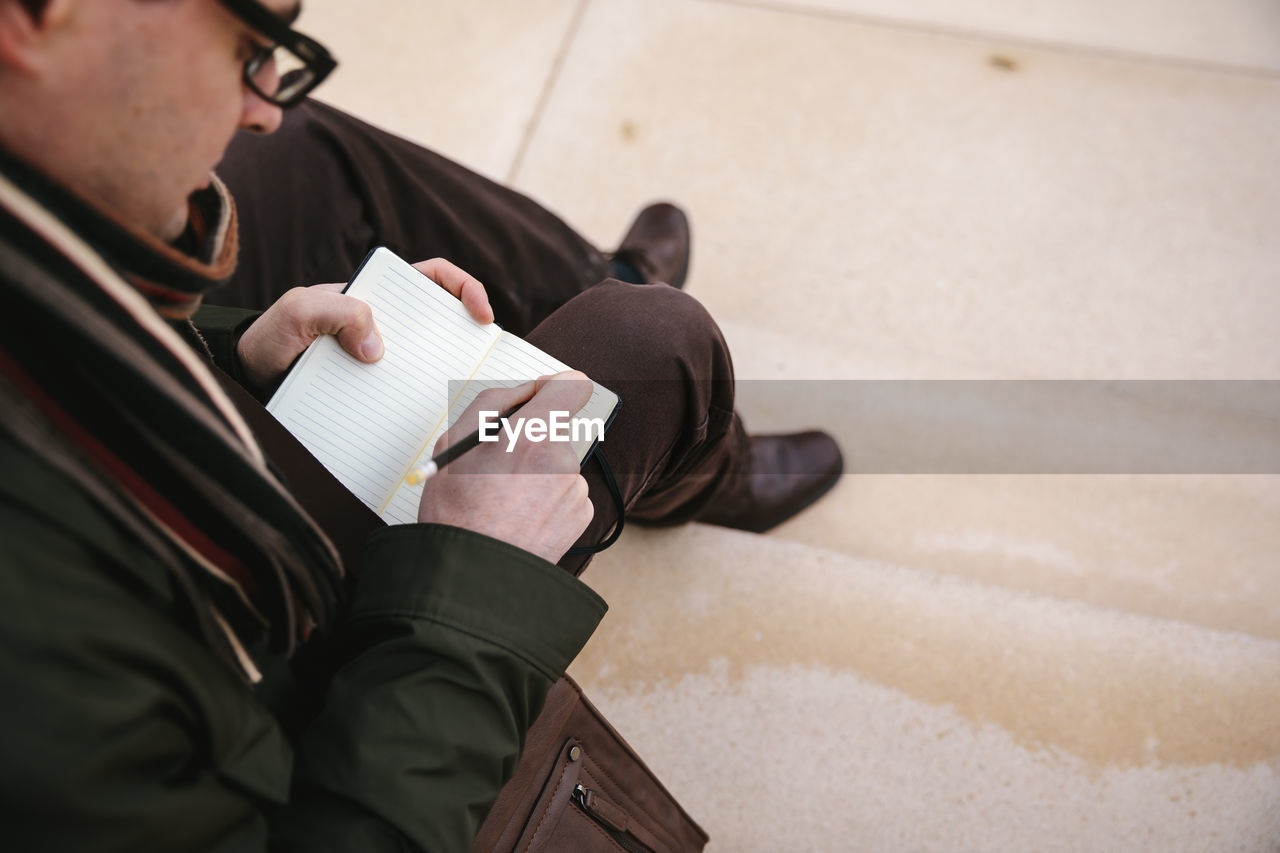 High angle view of man writing in diary