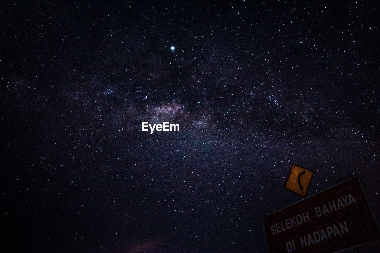 LOW ANGLE VIEW OF ILLUMINATED STAR FIELD AGAINST SKY