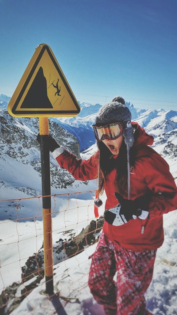 Woman standing by sign on snowcapped mountain