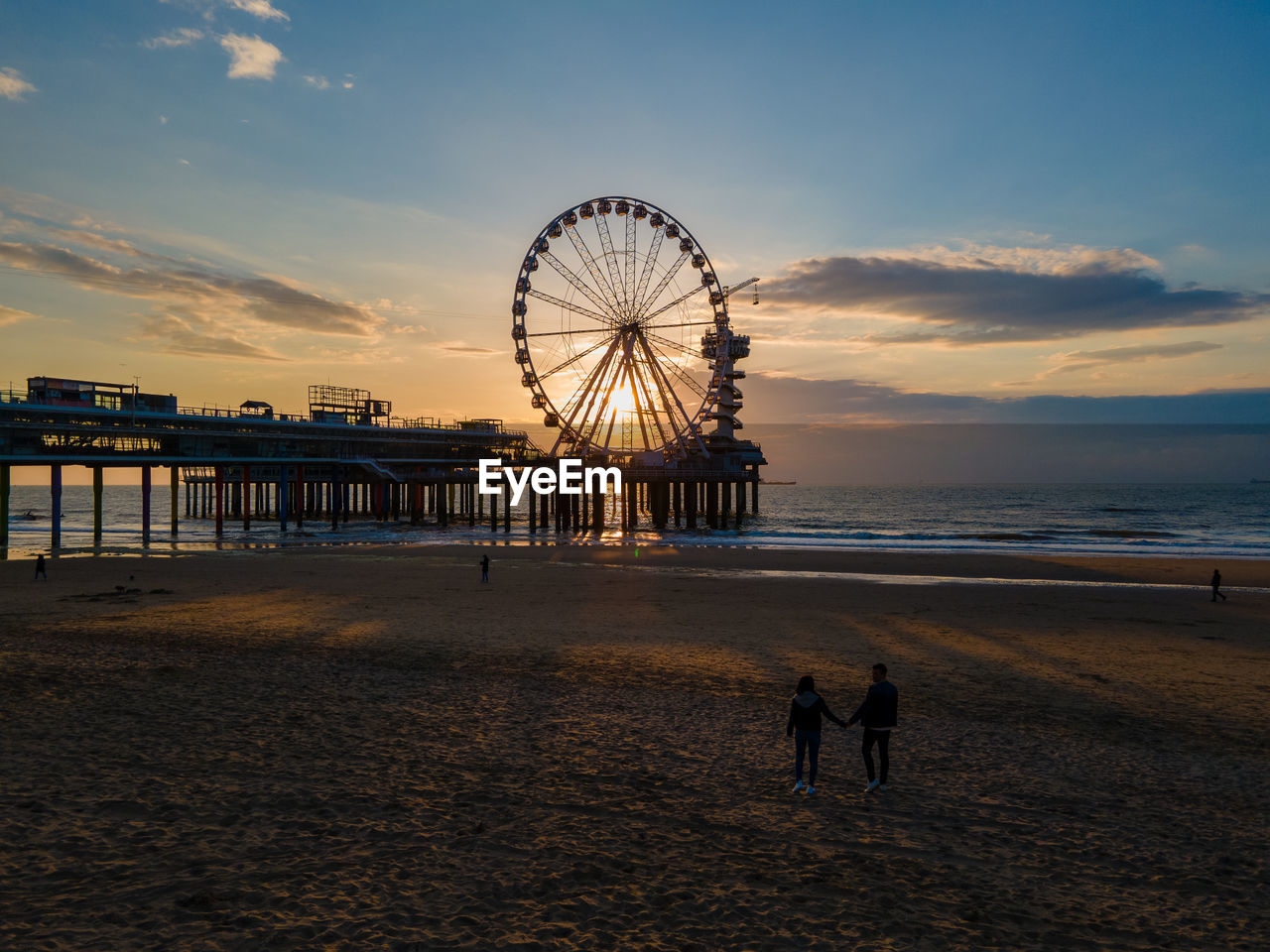 SILHOUETTE FERRIS WHEEL BY SEA AGAINST SKY DURING SUNSET