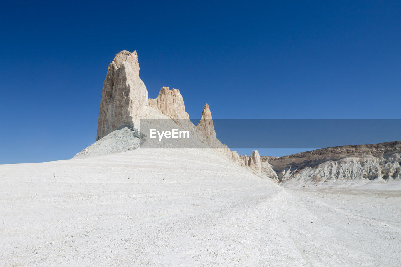 low angle view of rock formations in desert against clear blue sky