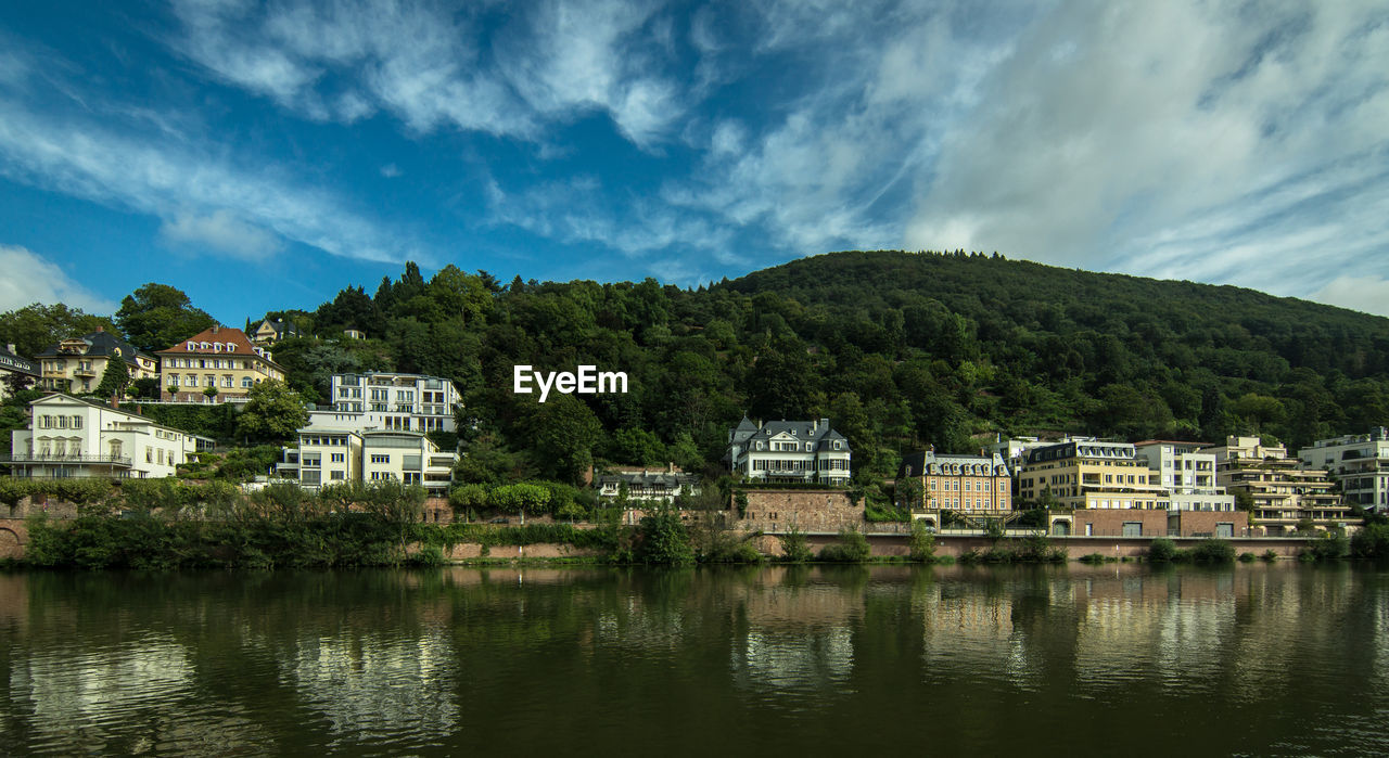 Buildings by lake against sky