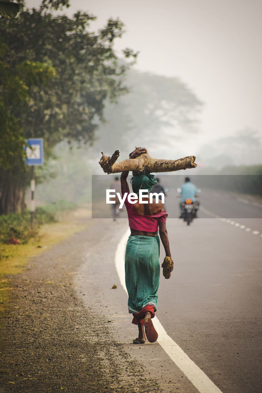Rear view of woman walking on road