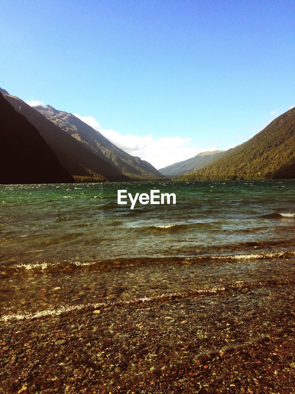 SCENIC VIEW OF SEA AND MOUNTAINS AGAINST BLUE SKY