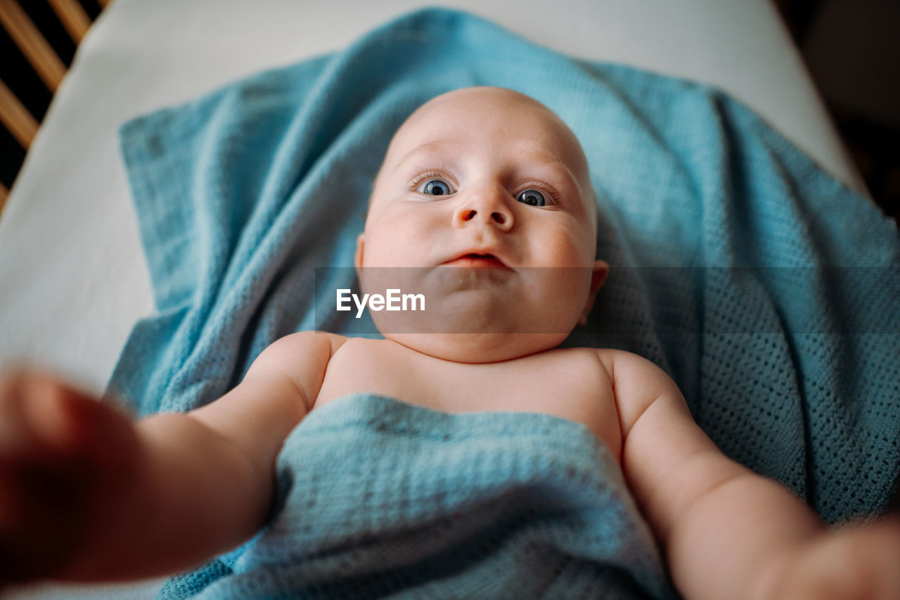 Baby toddler taking a selfie in crib. holding smartphone. scared face