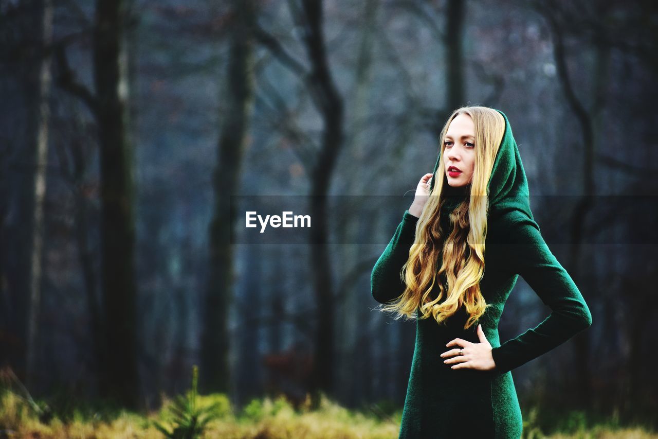 Woman in witch costume looking away while standing at forest