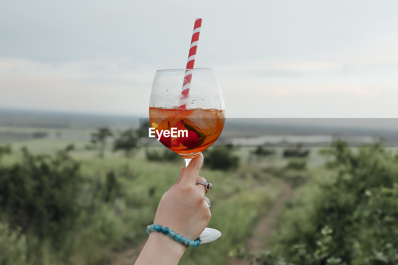 PERSON HOLDING DRINK AGAINST SEA