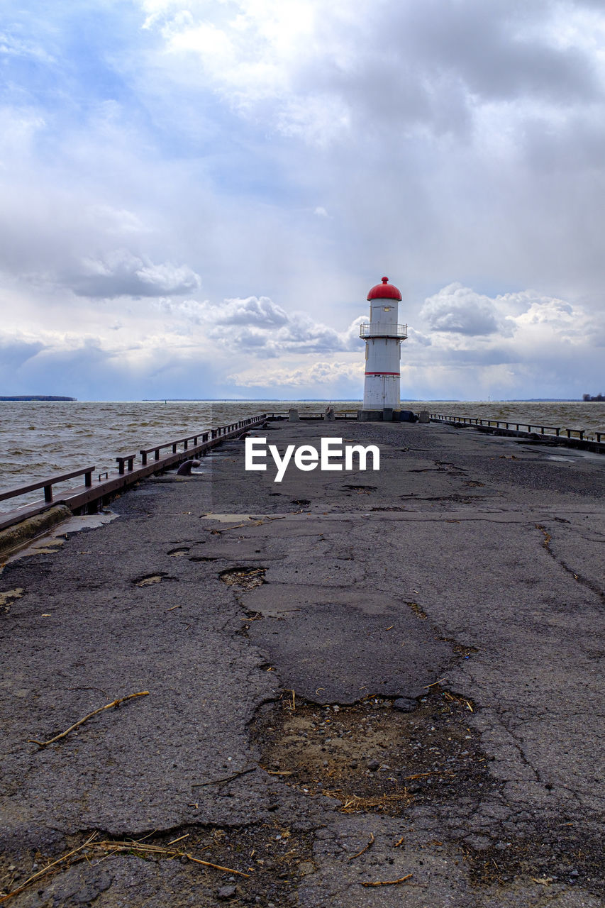 LIGHTHOUSE BY SEA AND BUILDINGS AGAINST SKY