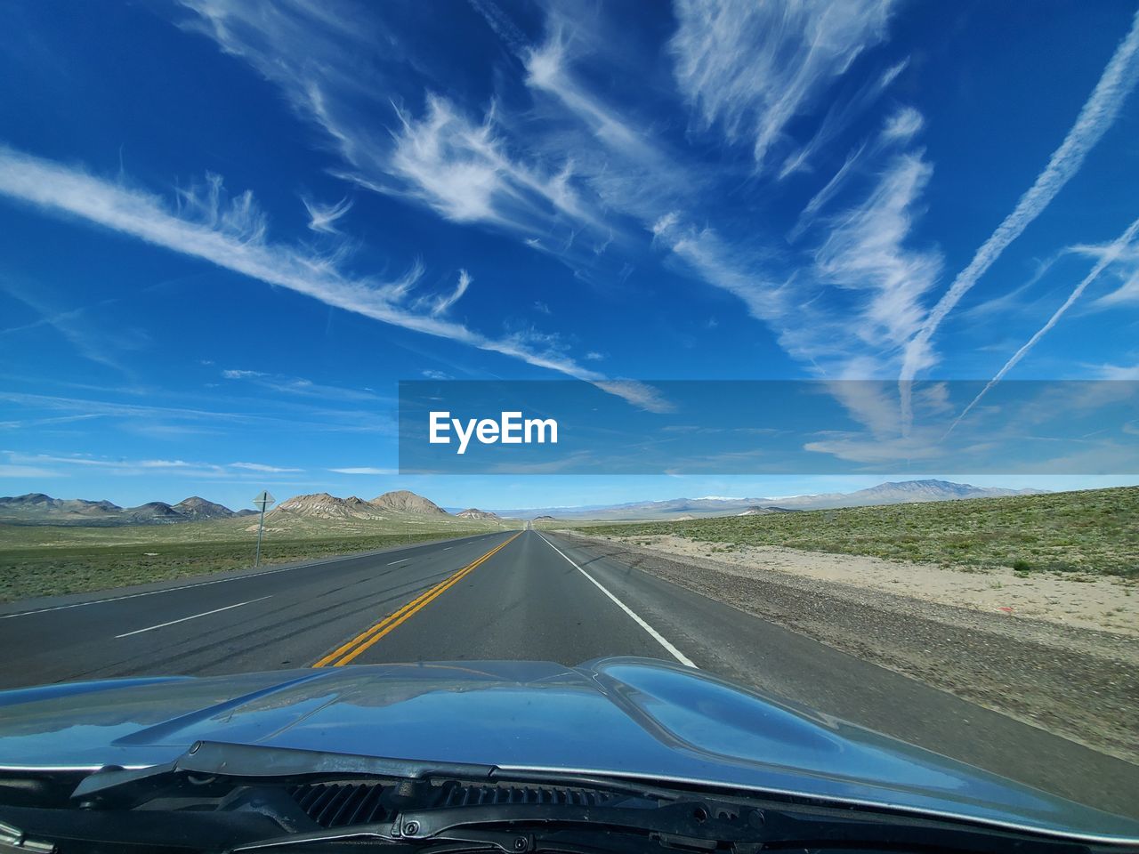 Road against blue sky seen through car windshield