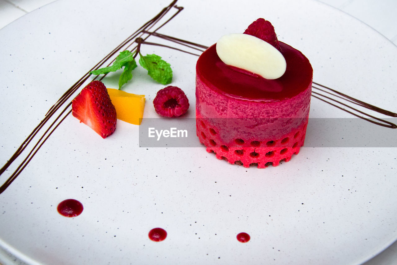 Close-up of raspberry and lemon curd cake decorated with strawberry, mango, and raspberry