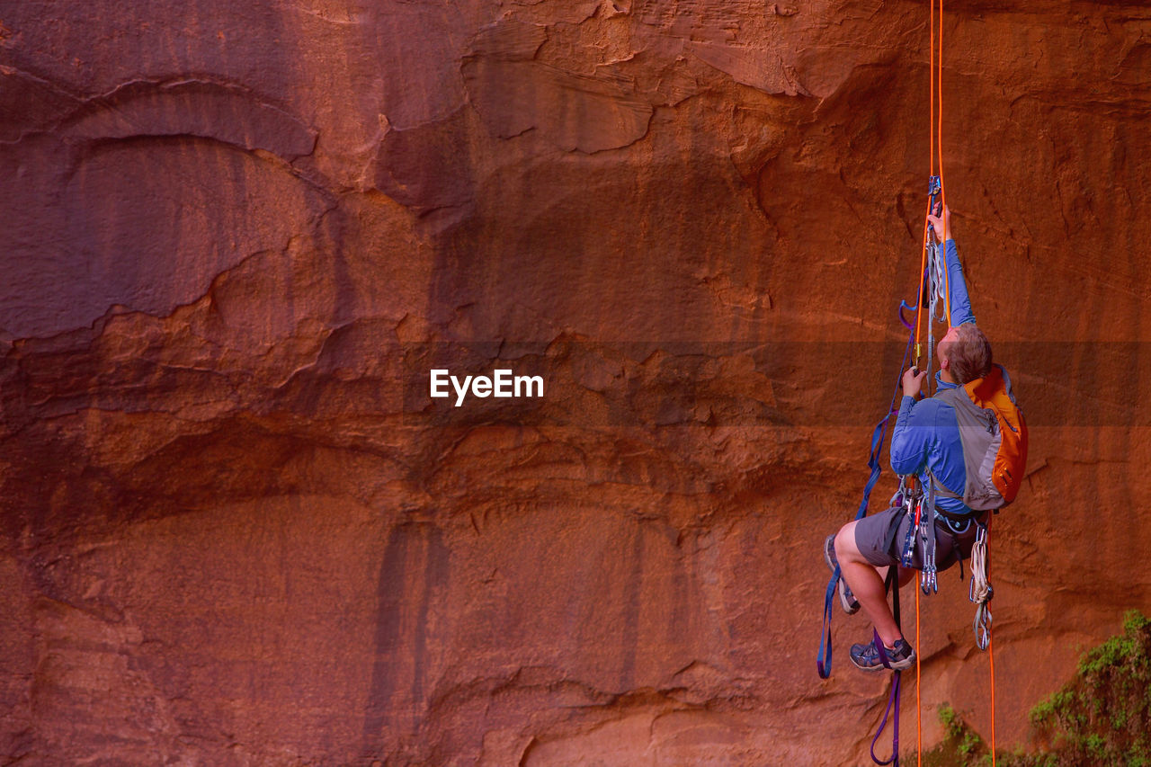 Man rappelling into cave at escalante's giant staircase