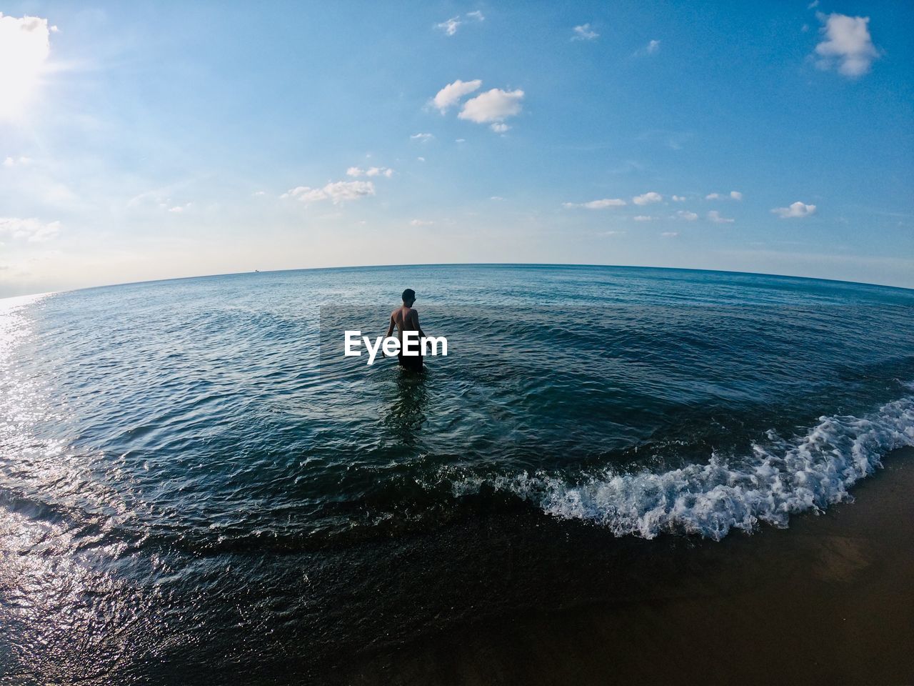 Rear view of man standing in sea against sky