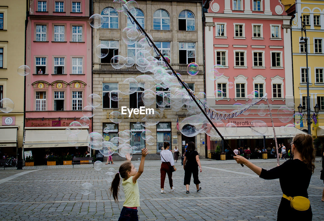 PEOPLE ON STREET AMIDST BUILDINGS IN CITY