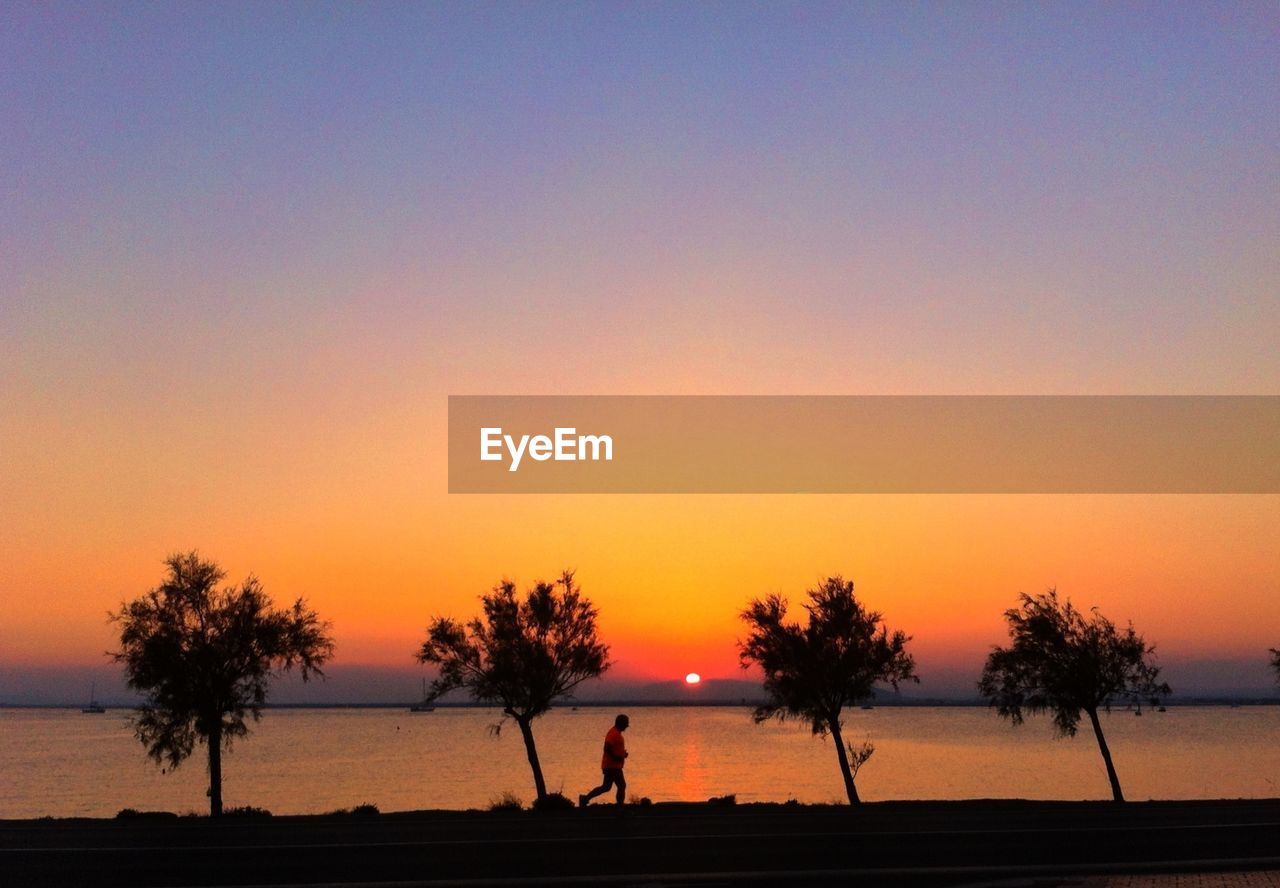 Man running by lake during sunset