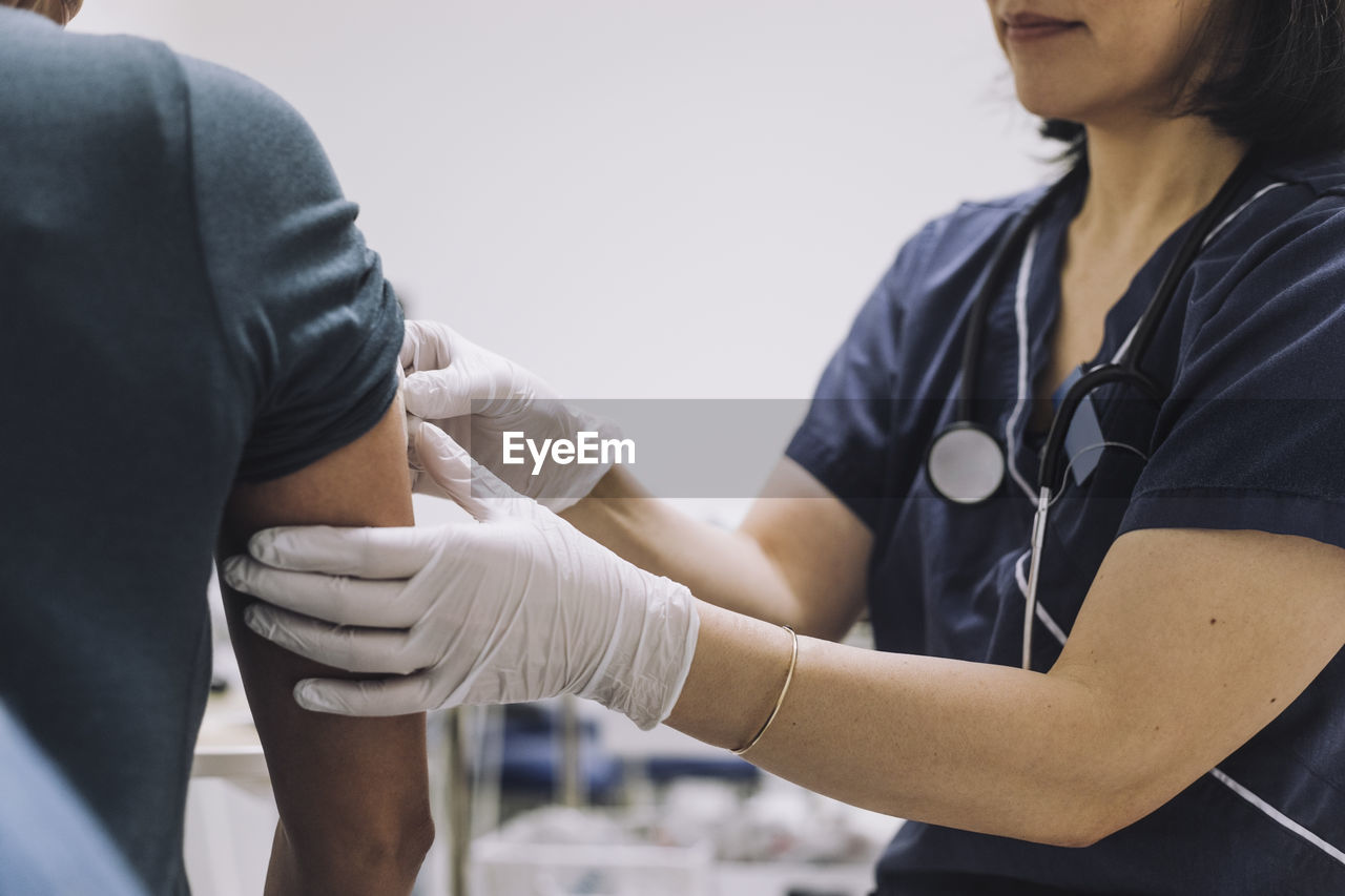 Midsection of female gynecologist wearing protective gloves examining patient in medical clinic