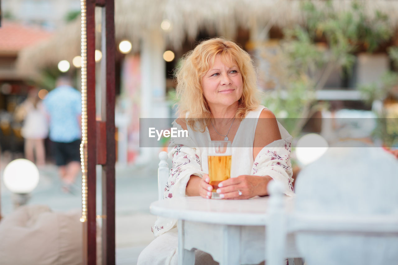 Portrait of woman drinking beer at beach cafe