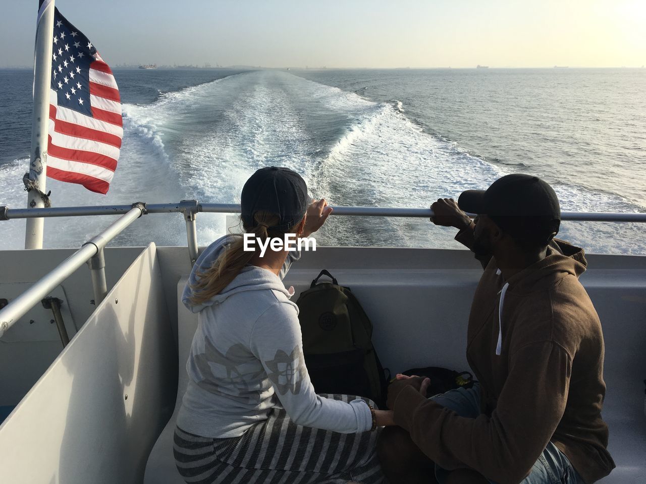 Man and woman sitting on boat in sea against sky